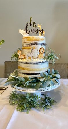 a three tiered cake sitting on top of a table next to green plants and greenery