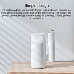 two white vases sitting next to each other on top of a wooden table in front of a wall