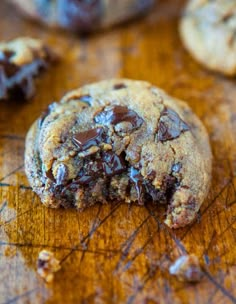 a chocolate chip cookie on a cutting board with one bite taken out and the other half eaten