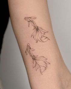 a woman's arm with two goldfish tattoos on the left side of her body