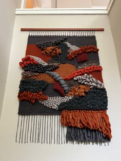 a wall hanging made out of different colored yarns