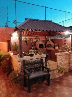 an outdoor kitchen is lit up at night with lights shining on the grill and bench