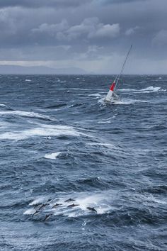 a sailboat is in the middle of choppy water on an overcast day