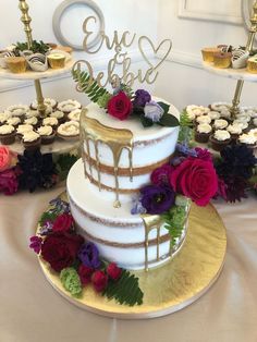 a three tiered cake on a table with cupcakes