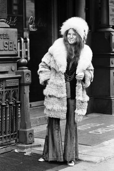 an old black and white photo of a woman wearing a fur coat on the street