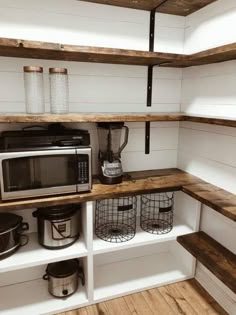 a kitchen area with shelves, pots and pans on the shelf next to an open microwave oven