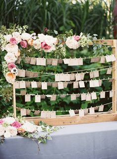 a wooden frame with flowers and notes attached to the sides is sitting on a table