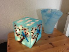 a blue vase sitting on top of a wooden table next to a light up cube