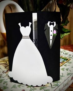 a paper cutout of a bride and groom on a table next to a vase with flowers