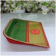 a red and green tray with flowers on the side sitting on a white table next to some flowers