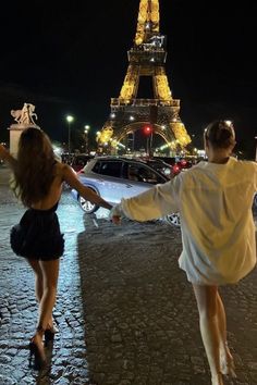 two people holding hands in front of the eiffel tower