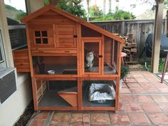 a large wooden house with two cats in it's cages on the outside