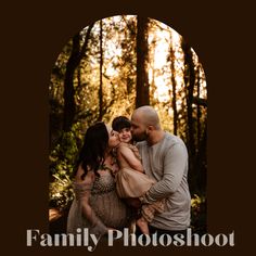 a man and woman hugging each other in the woods with trees behind them at sunset