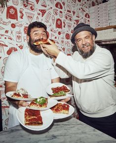 two men are eating pizza at a restaurant