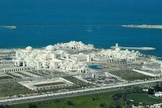 an aerial view of a large white building in the middle of some water and land