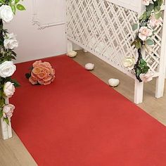 a red carpet with white flowers and greenery on the floor in front of it