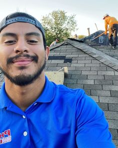 a man in blue shirt standing on top of a roof