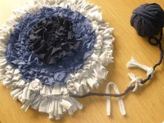 a blue and white hat sitting on top of a table next to a ball of yarn