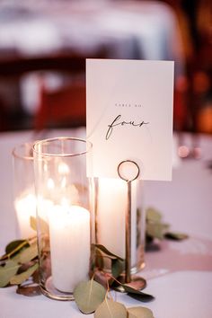 a table topped with candles and cards on top of a white table cloth covered table