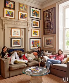 three women sitting on couches in a living room with pictures hanging on the wall