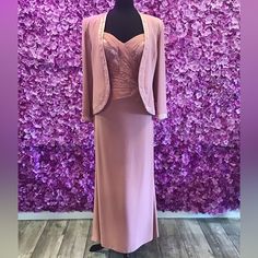 a dress and jacket are on display in front of a purple flowered wall,