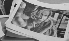 black and white photograph of woman in fur coat next to photos on table with papers