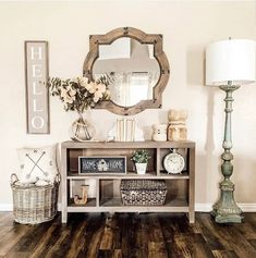 a living room with wooden floors and white walls, a mirror on top of the table