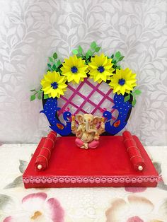 an elephant figurine sitting on top of a red mat with flowers in it