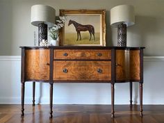 two lamps are sitting on top of a wooden dresser with a horse painting above it