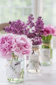 three mason jars with flowers in them sitting on a table