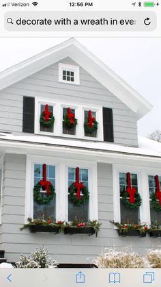 a house decorated for christmas with wreaths on the windows