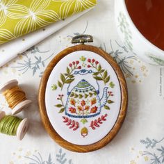 an embroidery kit with a teapot and spool of thread