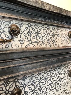 an ornate black and white dresser with brass pulls on the drawer knobs is seen in this image