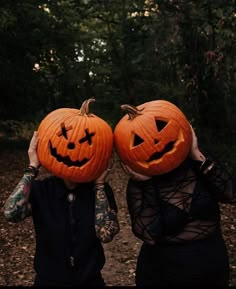 two people holding pumpkins with faces carved to look like jack - o'- lanterns