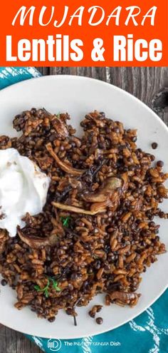 a white plate topped with lentils and rice next to a bowl of sour cream