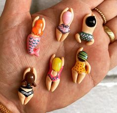 a person's hand holding six miniature figurines in different shapes and sizes