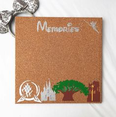 a cork board with the words memories written on it next to two silver mouse ears