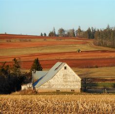 an old barn sits in the middle of a field