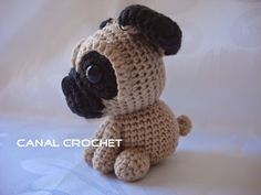 a small crocheted pug dog sitting on top of a white tablecloth