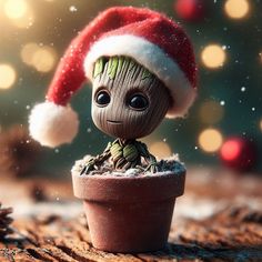 a baby groote doll wearing a santa hat sitting in a potted plant