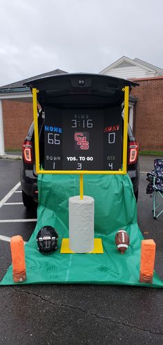 the back end of a car that is parked in a parking lot with an electronic clock on it