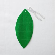 a pair of scissors sitting on top of a piece of green felt next to a leaf