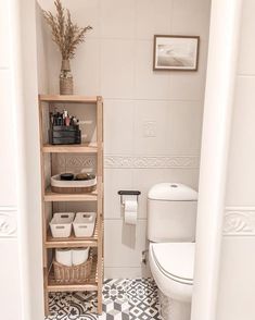 a white toilet sitting in a bathroom next to a wooden shelf filled with containers and baskets