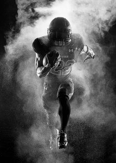 a black and white photo of a football player running with the ball in his hand