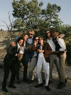 a group of people standing next to each other in front of trees and dirt ground