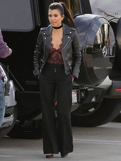 a woman wearing black pants and a leather jacket