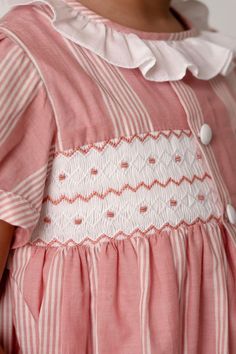 Designed in classic pink with white stripes, the Sidonie is a dress that will see your little ones through the seasons ahead in true style. The pretty pink dress has a classic Annafie silhouette with delicate puffed cap sleeves and a white frilled collar. The dress features hand-smocked front waist detailing and four white fabric covered buttons on the front. Our dresses are lined in cotton to create a perfect flare for twirling and dancing like everybody’s watching. The Sidonie has fabric cover Pretty Pink Dress, Frilled Collar, Girls Smocked Dresses, Popcorn Gift, Hand Smock, Shirt Dress Style, Smocked Dress, Fabric Covered Button, The Seasons