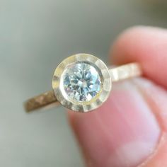 a close up of a person holding a ring with a diamond in it's center