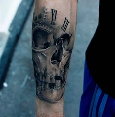 a man's arm with a clock and skull tattoo on it