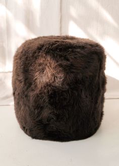 a brown fur covered ottoman sitting on top of a white table